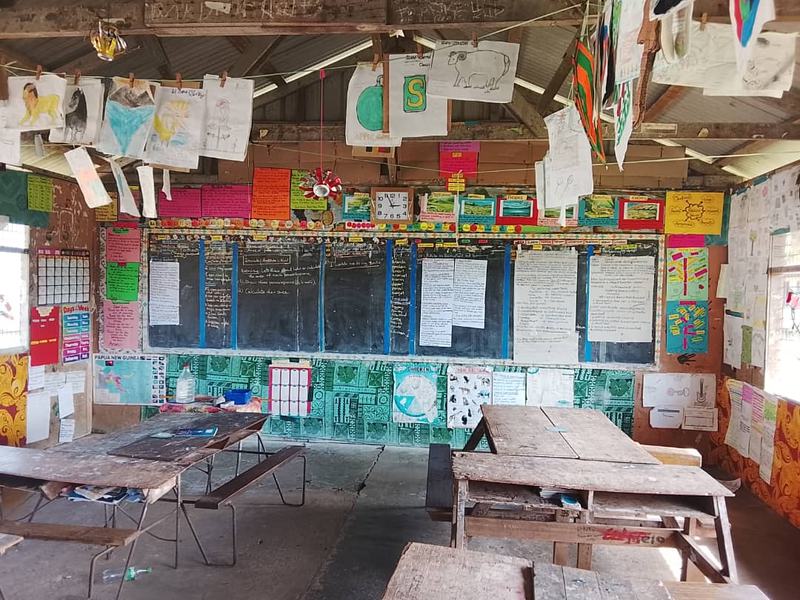 A classroom in East Sepik Province, its walls and rafters covered with handmade student work, charts and lesson notes.